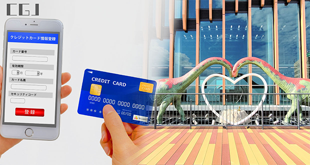 クレジットカードとスマホを持つ手元と福井駅の恐竜の模型