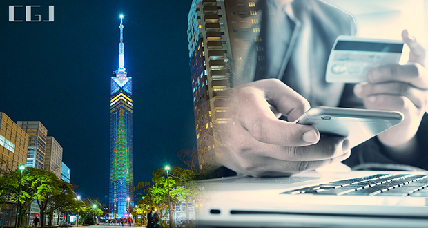 夜の福岡タワーとクレジットカード情報を入力する男性