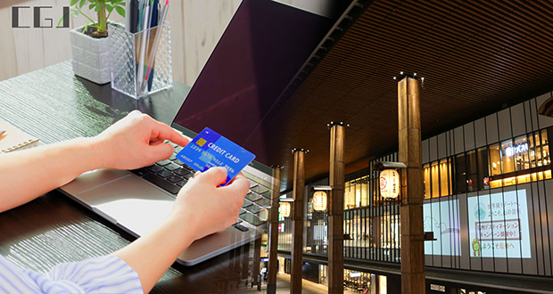 クレジットカードを持つ女性の手と長野駅